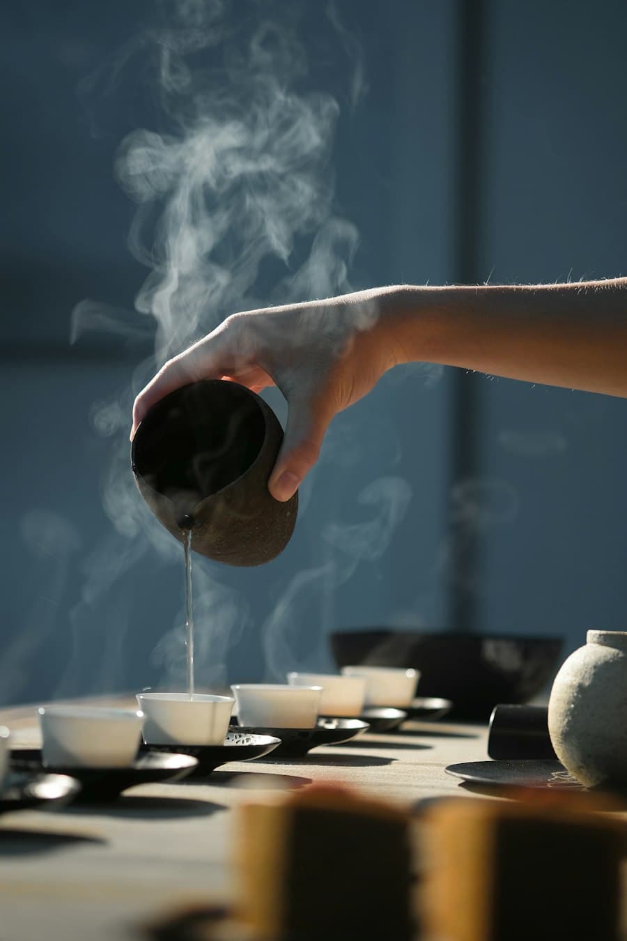 Tea being poured from a small clay pot in low light
