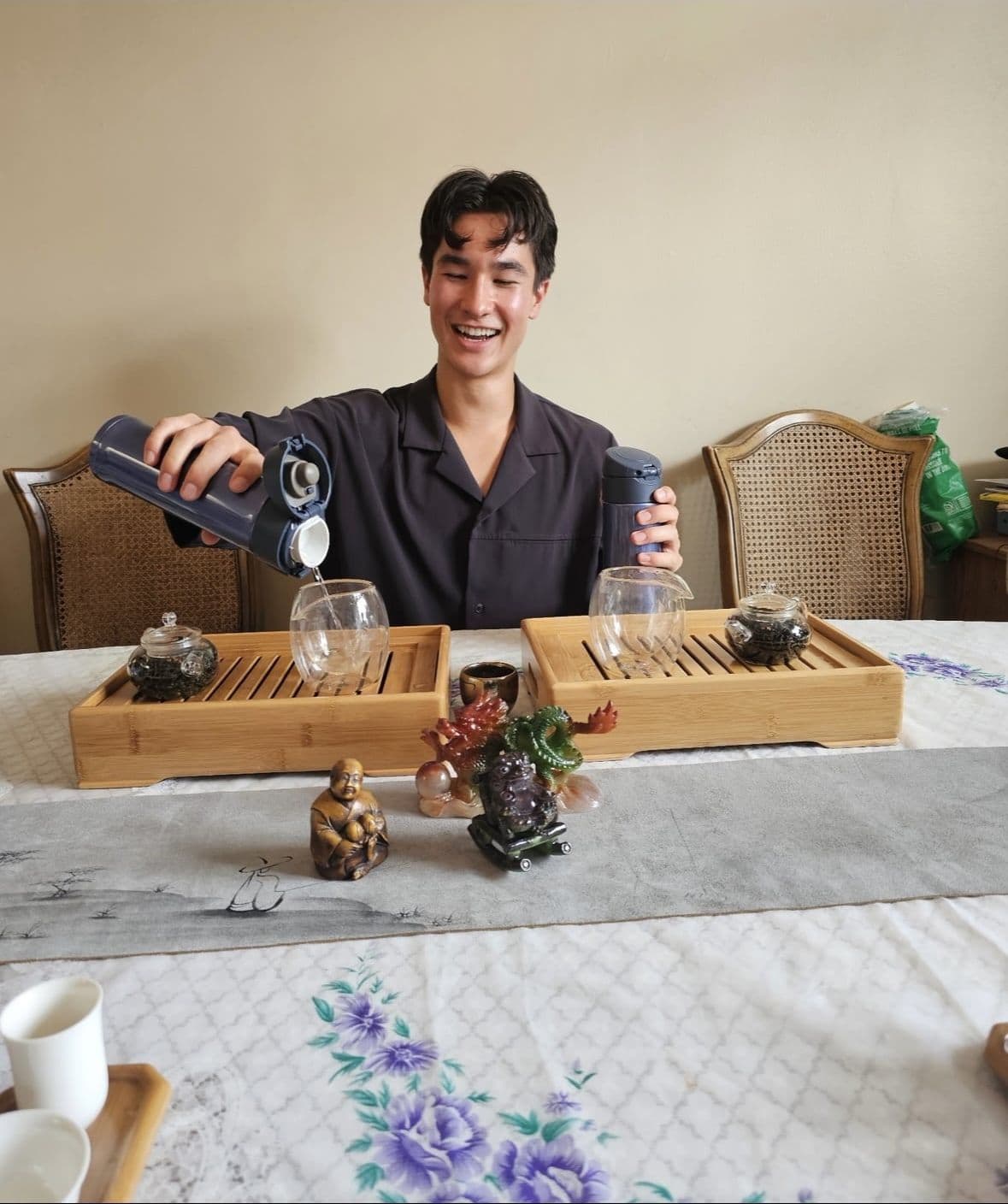 Ethan Holtzman smiling while pouring tea for guests during a ceremony